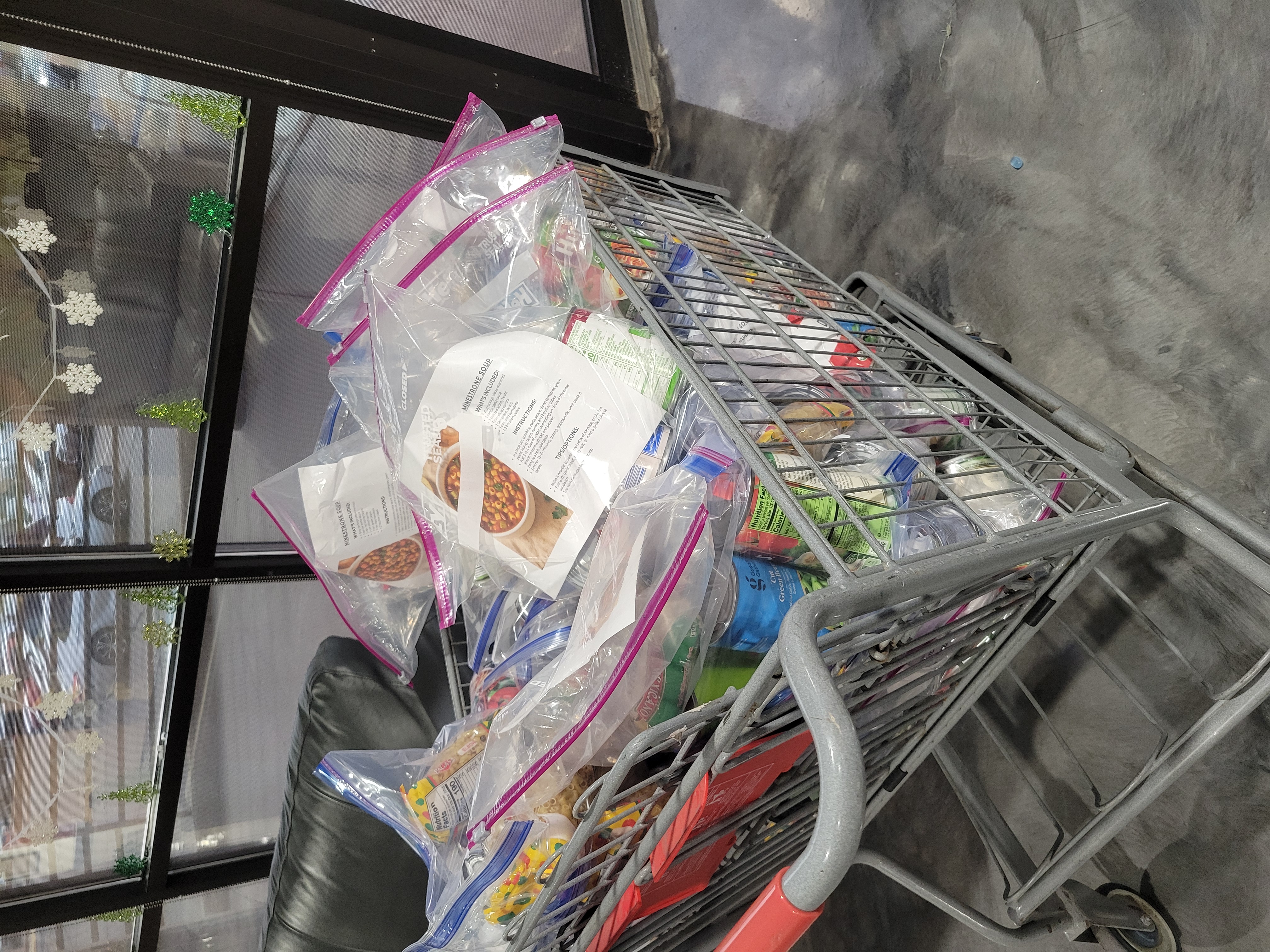Shopping cart filled with zip lock bags of ingredients and recipe card for minestrone soup.